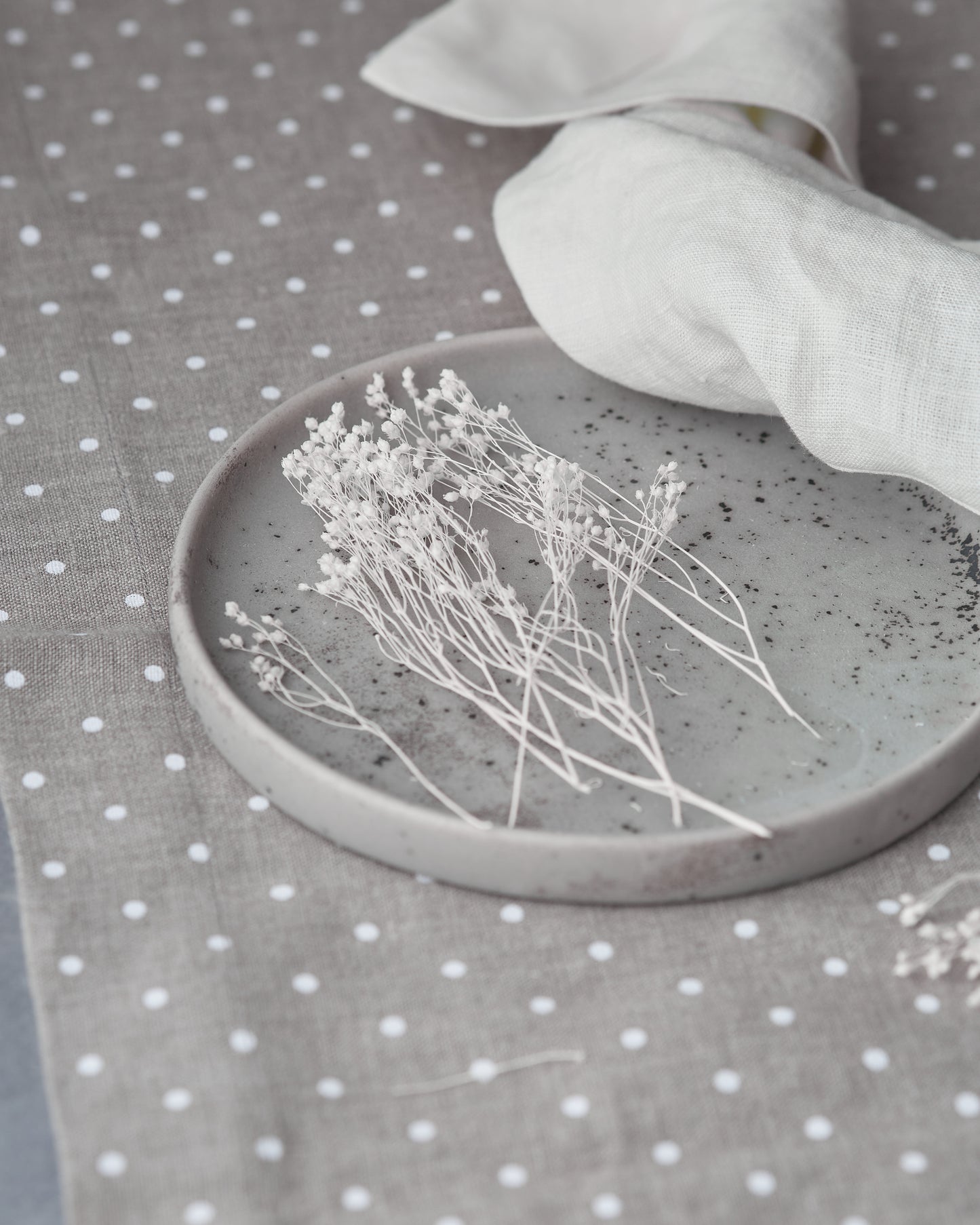 Ceramic dish with dried flowers on a grey linen table runner