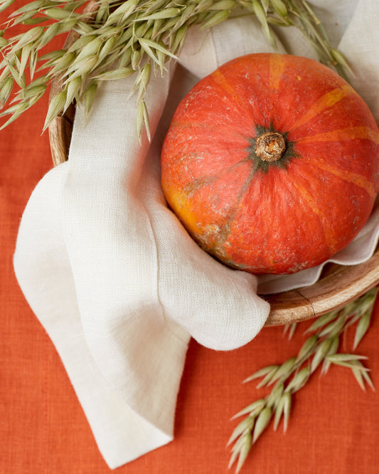Small pumpkin in a wooden bowl with a white linen napkin by Fine Dining 4 Home