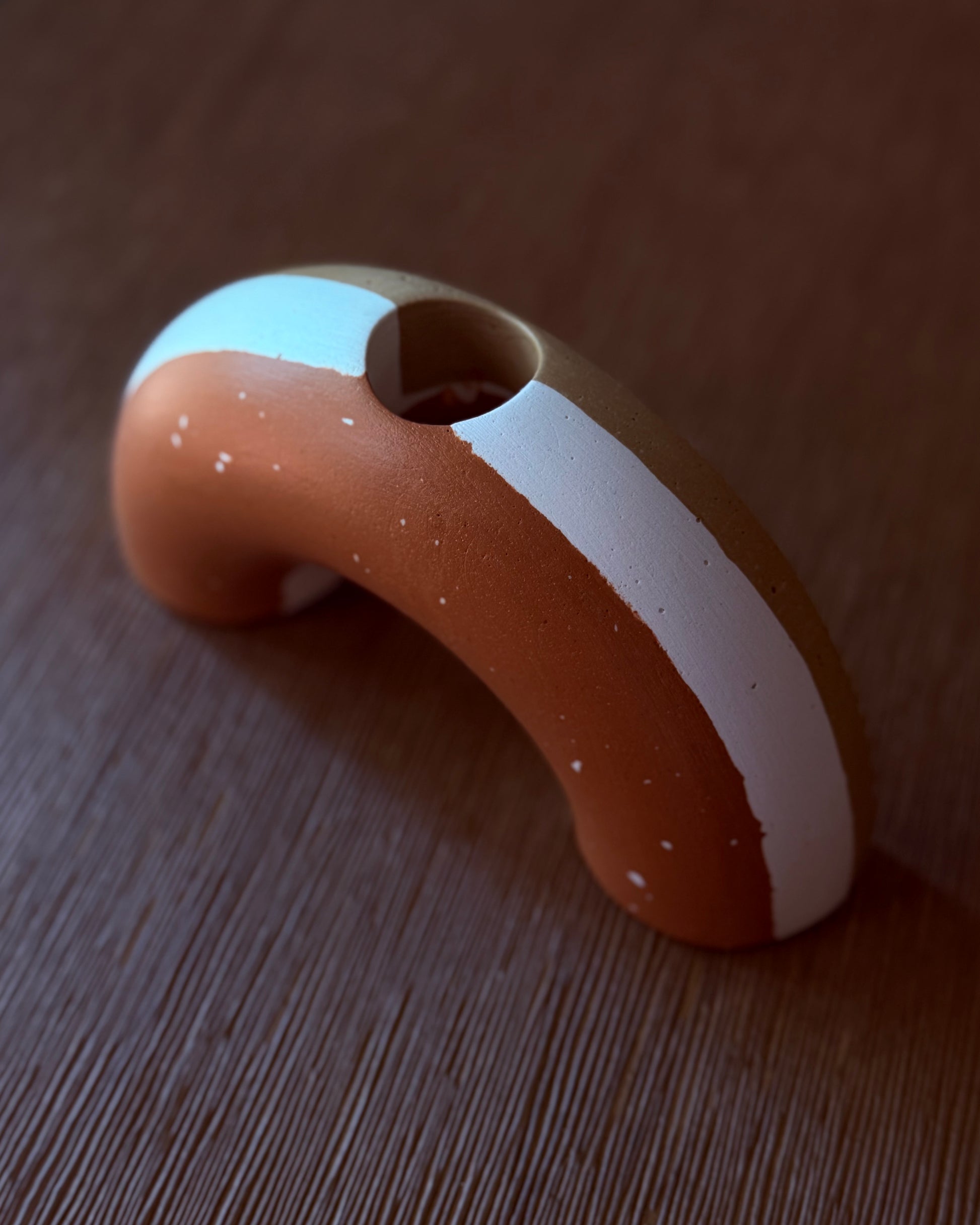 Ceramic handle with a white stripe on a wooden surface