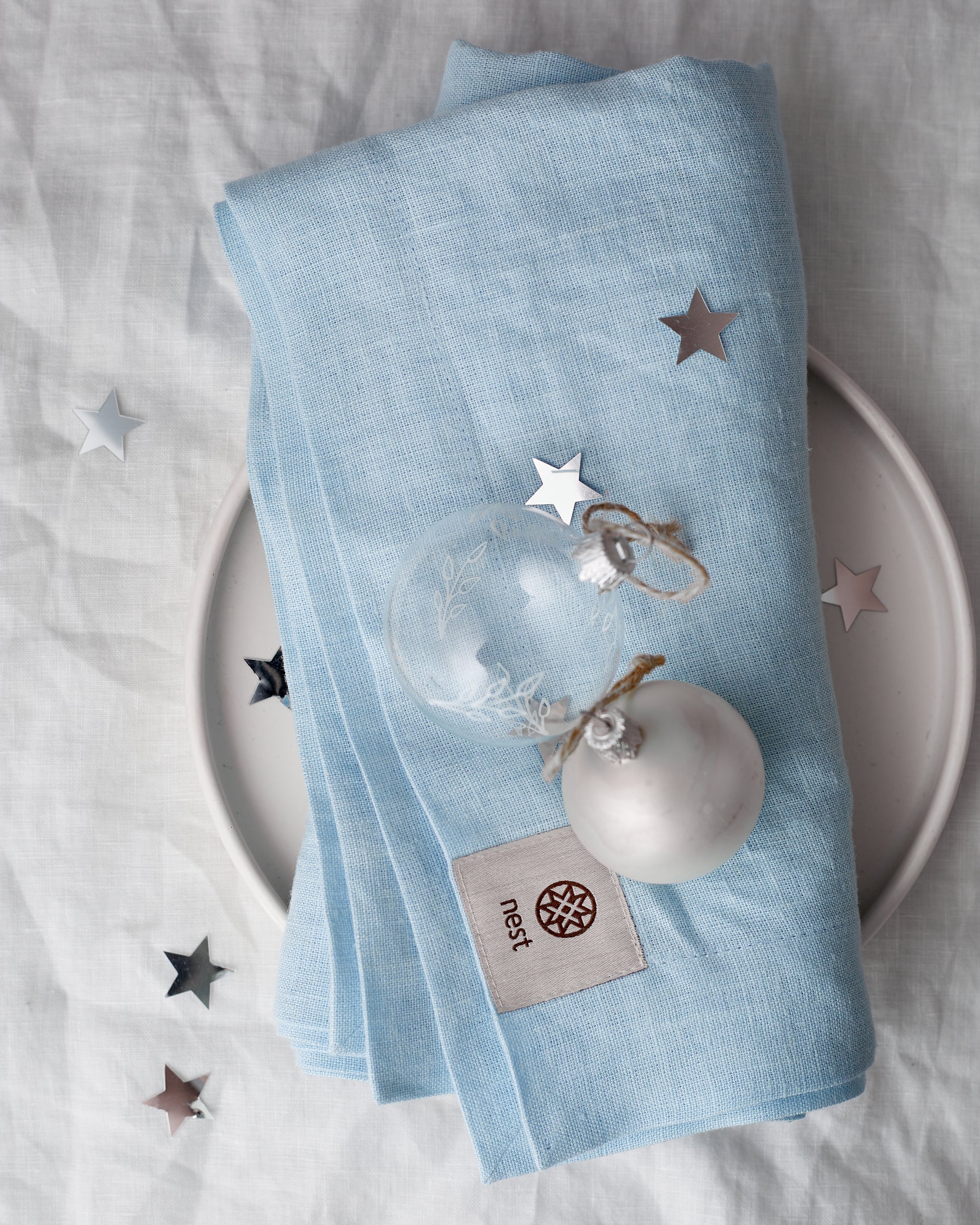 Light blue linen napkin with star confetti on a white plate styled for christmas table