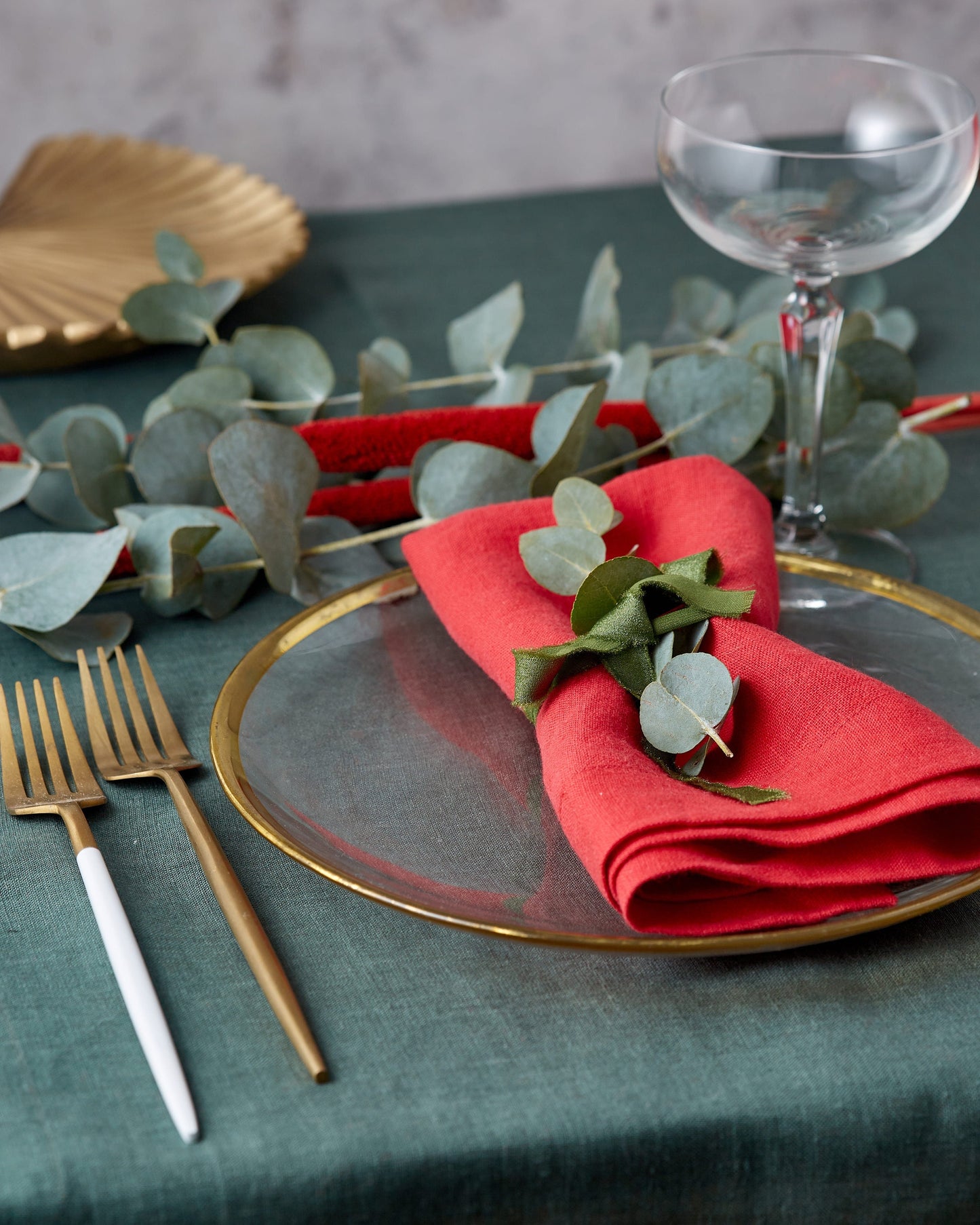 Stylish table setting with linen runner and napkin, eucalyptus table decor and golden flatware