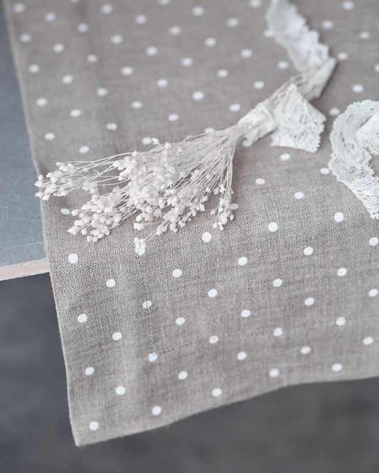 Gray table runner with white polka dots and a small bouquet of dried flowers 