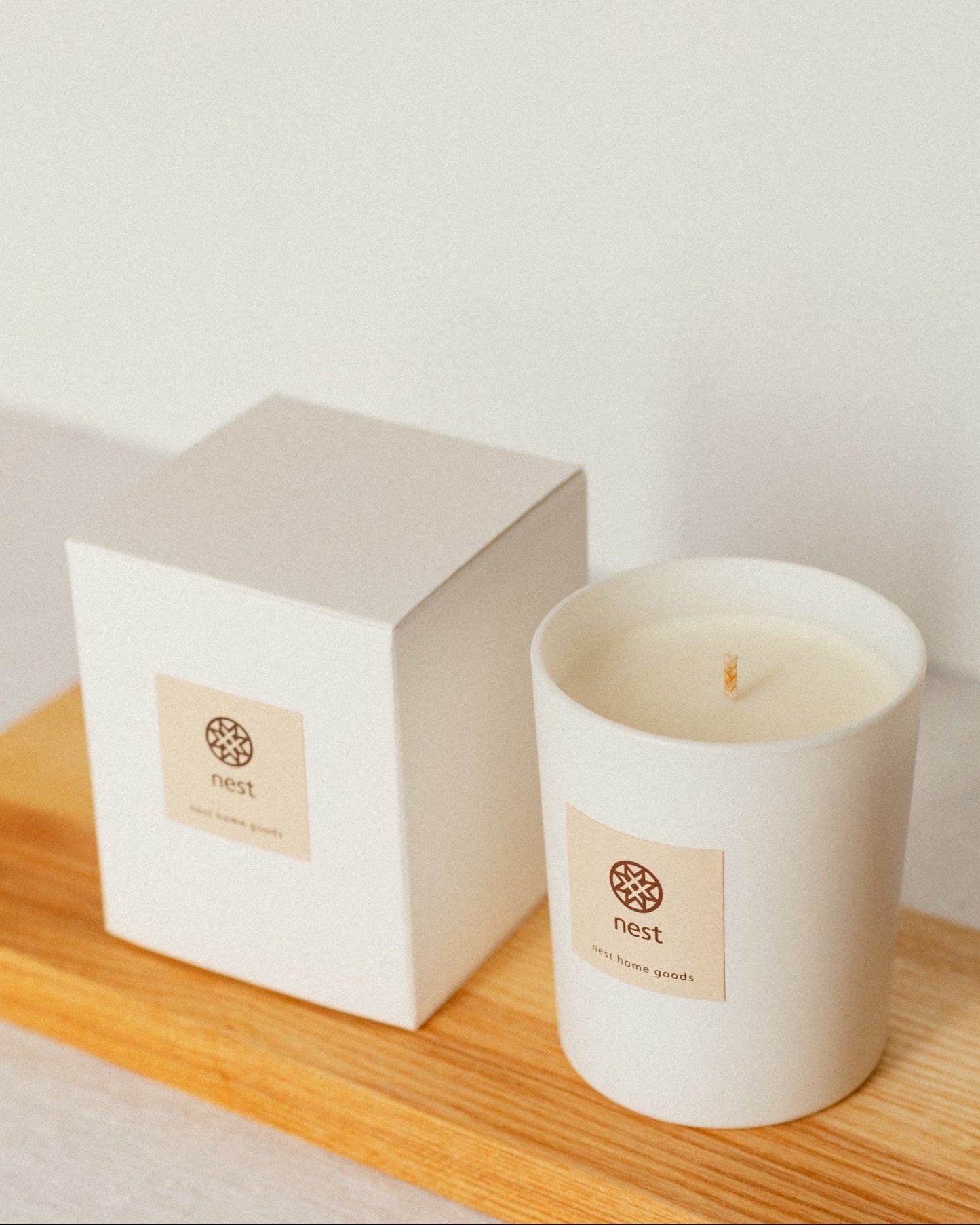 Minimalistic white candle and box with a label on a wooden surface, nest home goods collection for Fine Dining 4 Home