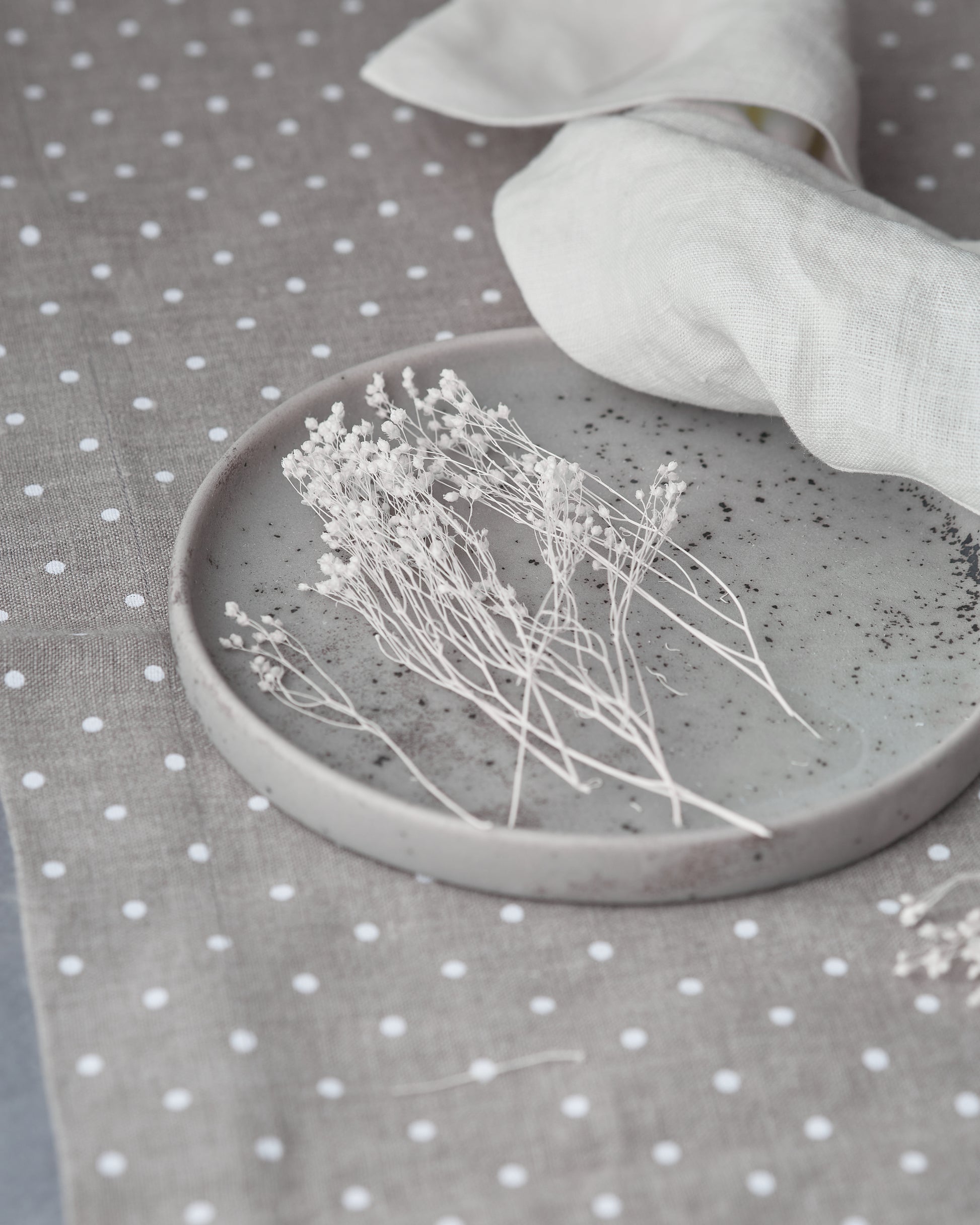 Ceramic dish with dried flowers on a grey linen table runner